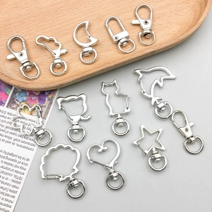 Various silver-colored shaped metal keychain hooks and lobster clasps on a tray