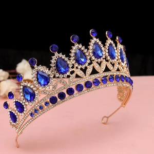 Dettaglio laterale di corona dorata vintage con gemme blu a goccia e strass lucidi