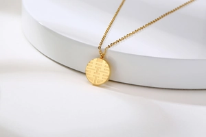 Detail of a golden round necklace pendant featuring an engraved Double Happiness symbol