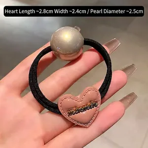 Détail du pendentif cœur rose avec relief métallique et perle sur un élastique à cheveux
