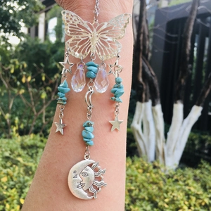 Detailed outdoor view of a metal butterfly suncatcher with star, moon and crystal charms