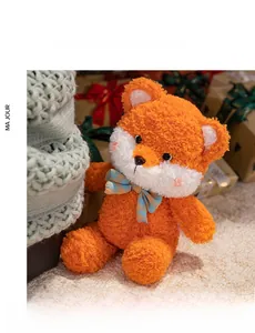 Detail of plush orange fox toy with soft long fur and a blue checkered bowtie on a carpet