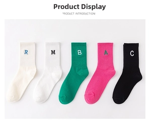 Detail of five colorful cotton crew socks with vibrant letter embroidery on a white base