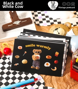 Close-up of vintage black postcard with cartoon bear illustration and smile warmly text