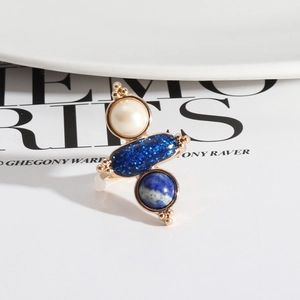 Detailed macro view of a gold ring featuring pearl, blue glitter, and lapis lazuli stones