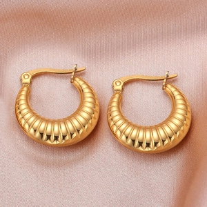 Detailed view of golden croissant earrings with shrimp texture on pink silk fabric