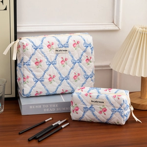 Detailed macro view of quilted makeup bags featuring blue bows and pink floral patterns