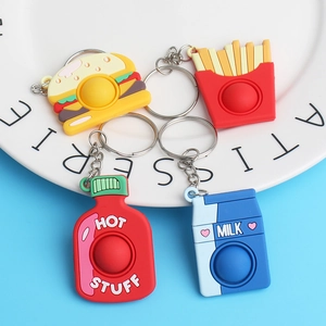 Squeeze toy food keychains set with burger, fries, and milk on a white patisserie plate
