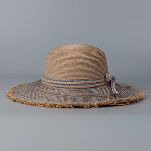 Detail of raffia sun hat featuring frayed edges and blue-grey striped ribbon trim
