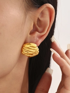 Close-up of textured golden irregular wavy earrings on model for a trendy look