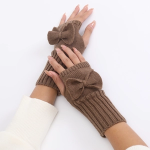 Close-up of brown knit fingerless gloves featuring a decorative large matching bow detail