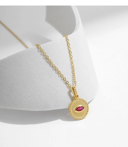 Close-up of gold s925 silver necklace with pink eye-shaped crystal pendant on white base