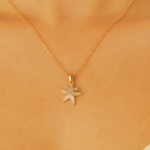 Dettaglio della collana dorata con ciondolo a stella marina in zirconi e madreperla