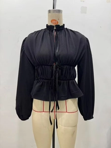 Detail der schwarzen Chiffonbluse mit Rüschen-Stehkragen und elastischem Bindegürtel