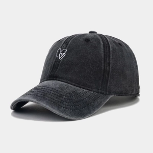 Détail du tissu denim délavé et broderie de cœur blanc sur une casquette de baseball