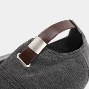 Detail of dark grey baseball cap with adjustable brown leather strap and silver buckle