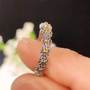 Makroaufnahme von Gänseblümchen-Ring in Silber mit gelben Emaille-Blüten und feinen Details
