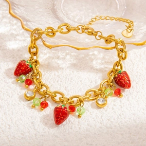 Detail of 18k gold plated stainless steel bracelet with red strawberry and beaded charms
