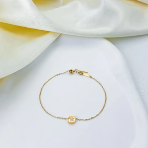 Elegante pulsera de acero de titanio con un delicado colgante de estrella en oro