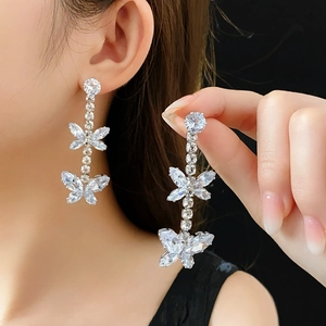 Gros plan de boucles d'oreilles papillon à pompons en zircone avec finition argentée