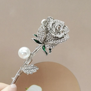 Detailed view of silver rose brooch with crystals, white pearl and green enamel accents