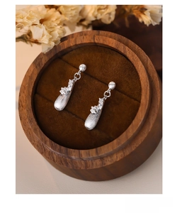 Close-up of S925 silver teardrop earrings with brushed texture on wooden jewelry box