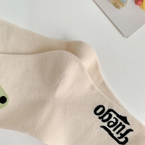 Detail of cream knitted cotton sock with black Fuego text and green polka dots