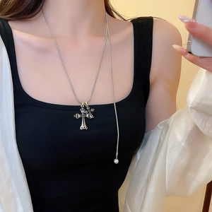 Dettaglio del ciondolo a croce argento con perla indossato su una catena alla moda