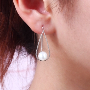 Elegant S925 silver pearl drop earrings in a teardrop frame worn by a model