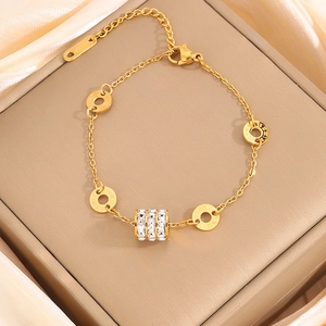 Detail of gold chain bracelet with Roman numeral discs and crystal cylinder charm