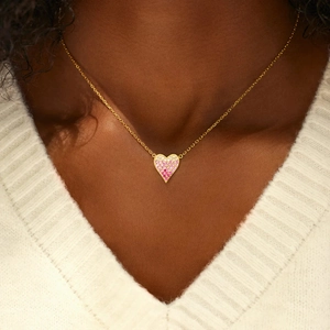 Close-up of pink and white gradient heart pendant on a thin gold chain worn by a model