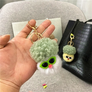 Detail of creative plush broccoli doll keychain with sunglasses hanging on a black bag