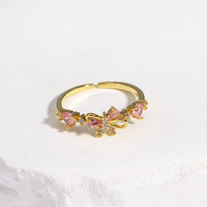 Detail of gold bow ring with pink heart zircon and sparkling crystal inlay