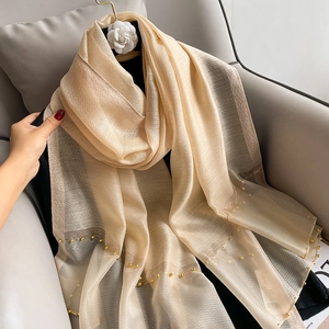 Detail of gold silk scarf with elegant beaded edges draped on a chair for texture