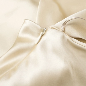 Close-up of champagne satin fabric showing fine stitching and invisible zipper detail