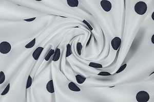 Macro detail of navy blue polka dot printed fabric with soft silk-like luster and drape