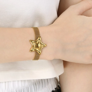 Close-up of golden mesh chain bracelet with a polished star charm on a female wrist