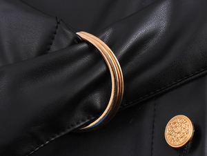 Detail of gold metal ring buckle and woven button on black leather halter dress
