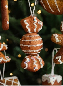 Close-up of brown gingerbread candy ornament with white frosting on a Christmas tree