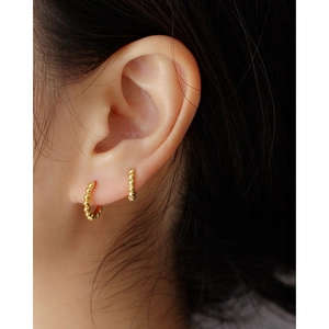 Close-up of gold beaded s925 sterling silver huggie hoop earrings worn on an ear