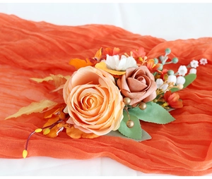 Détail d'un corsage d'épaule mariée avec roses pêche et feuilles sur tulle orange