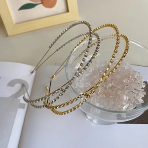Close-up of gold and silver alloy headbands with sparkling rhinestones in a glass bowl