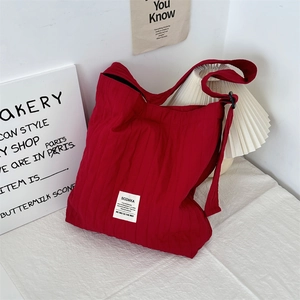 Close-up of red quilted canvas tote bag with vertical stripes and white logo patch