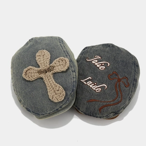Close-up of vintage washed denim berets with bow embroidery and crochet cross detail