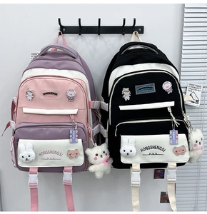 Detail of color-block school backpacks with cartoon badges and plush bear pendants