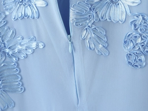 Détail d'une robe en résille bleu clair avec broderie satinée 3D et fermeture invisible