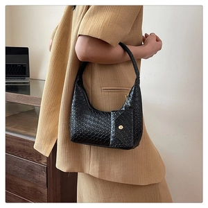 Model wearing a black woven shoulder bag with a matching small coin purse attachment