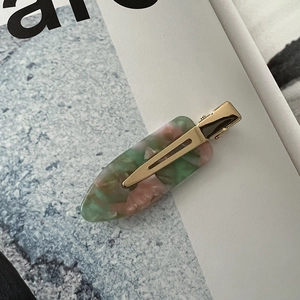 Close-up of marble acetate hair clip with golden metal clip on magazine page