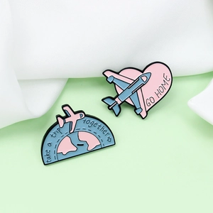 Travel enamel brooch set with pink heart and blue world plane pins on white cloth
