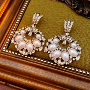 Vue détaillée de boucles d'oreilles vintage dorées avec perles et cristaux sur velours
